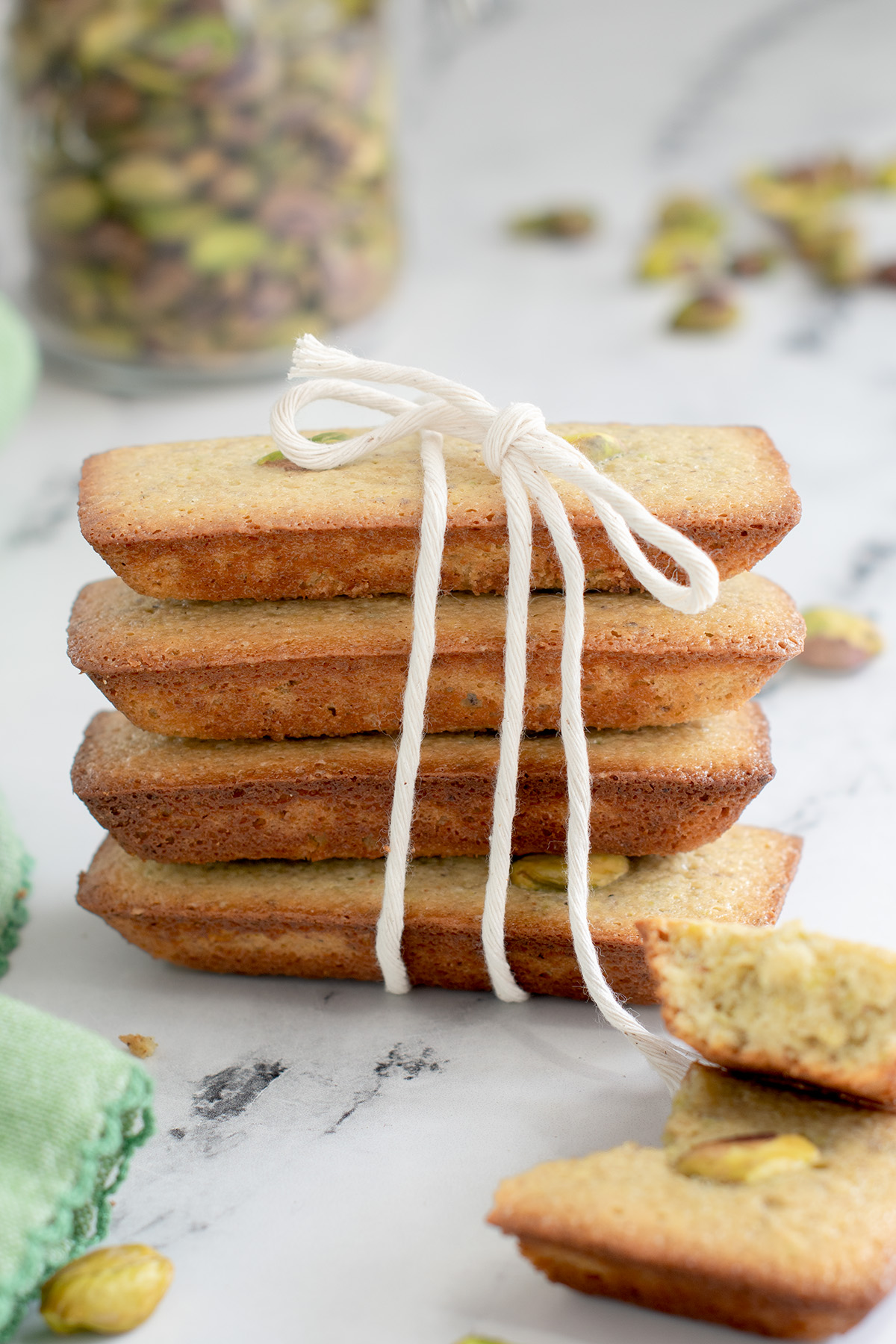 a stack of pistachio financiers tied in kitchen twine on a white plate.