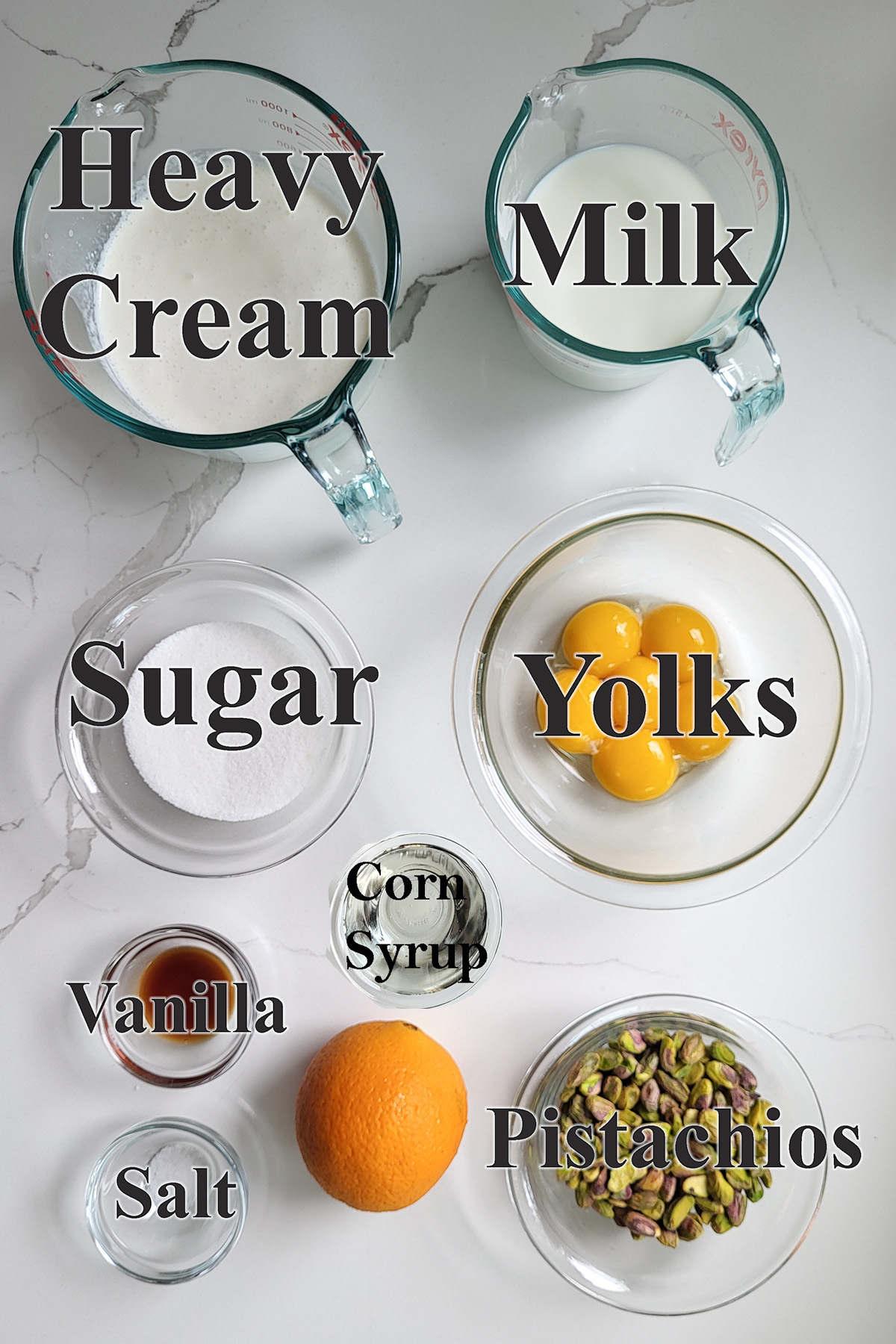 ingredients for pistachio ice cream in glass bowls on a white surface.