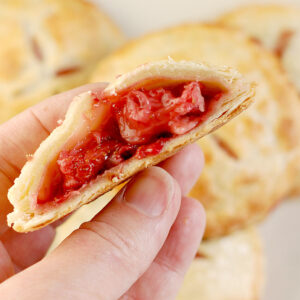 a hand holding a strawberry pie