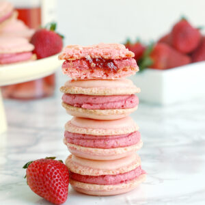 a stack of strawberry macarons on a white surface.