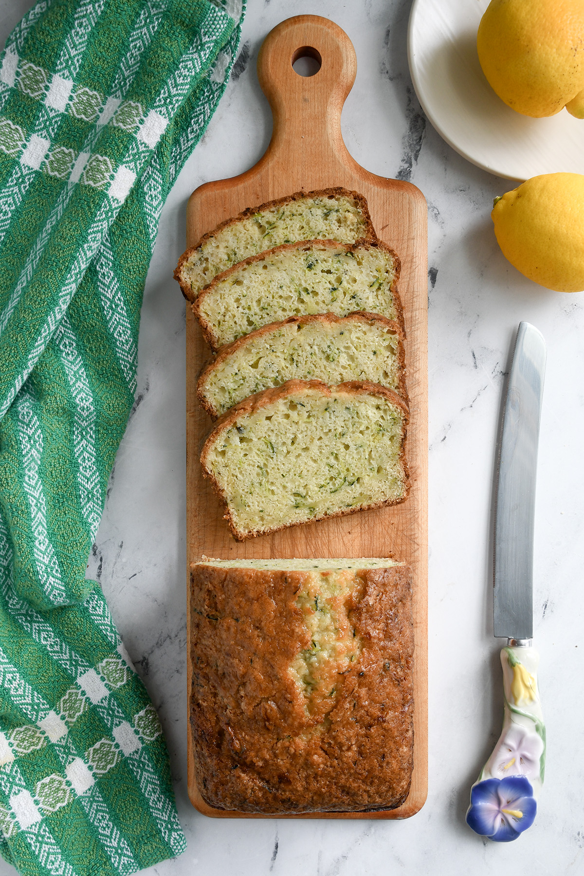 a partially sliced loaf of sourdough zucchini bread on a wood cutting board. 