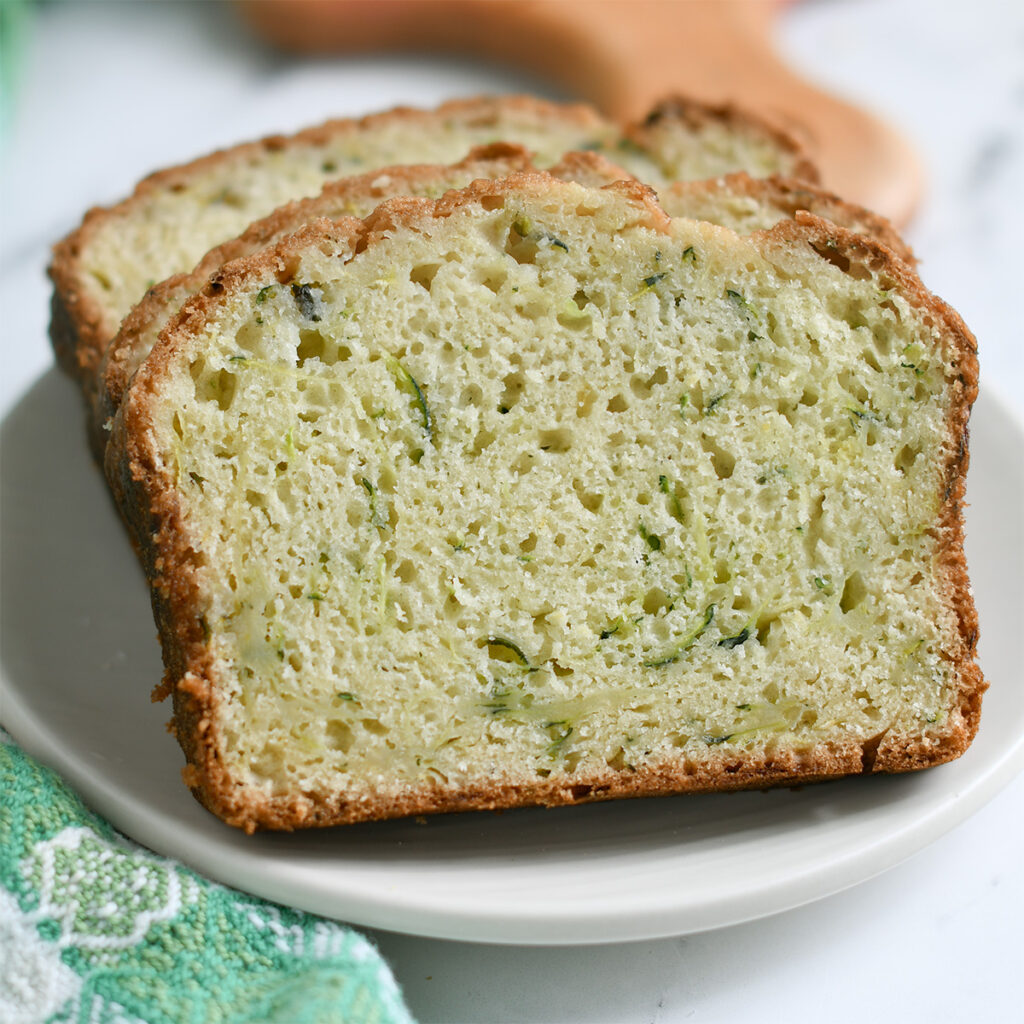 slices of sourdough zucchini bread on a white plate.