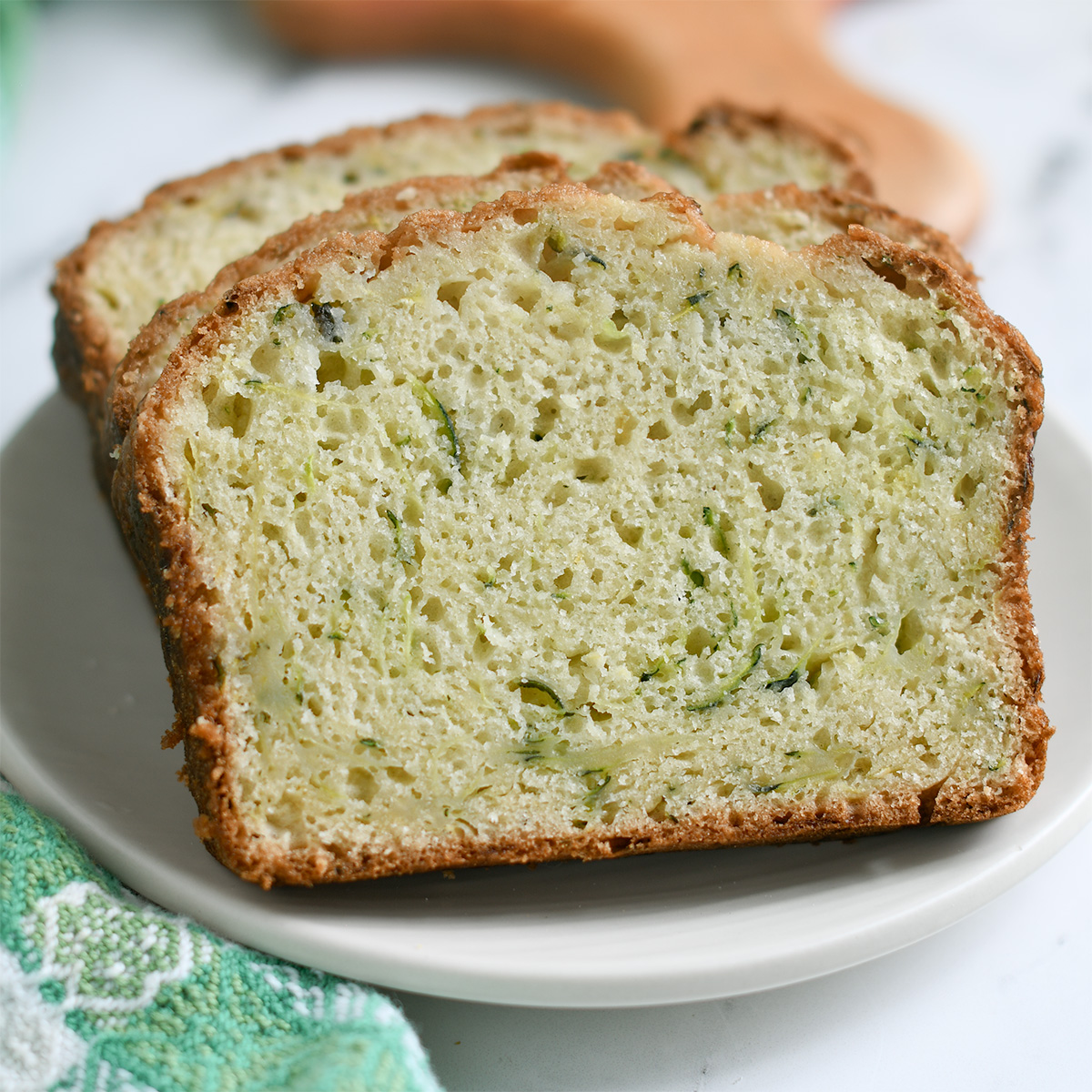 slices of sourdough zucchini bread on a white plate.