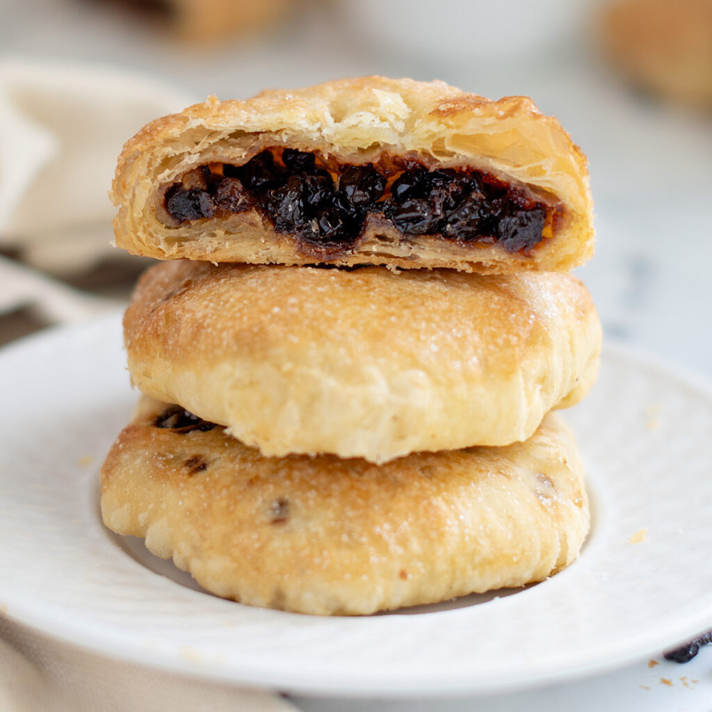 a stack of eccles cakes on a white plate.
