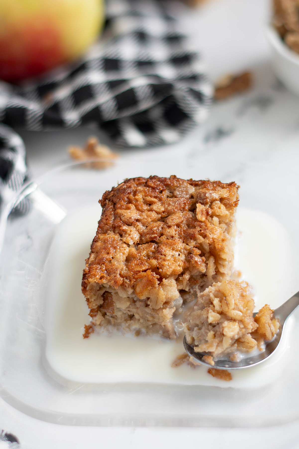 a slice of sourdough baked oatmeal on a plate with milk and a spoon.