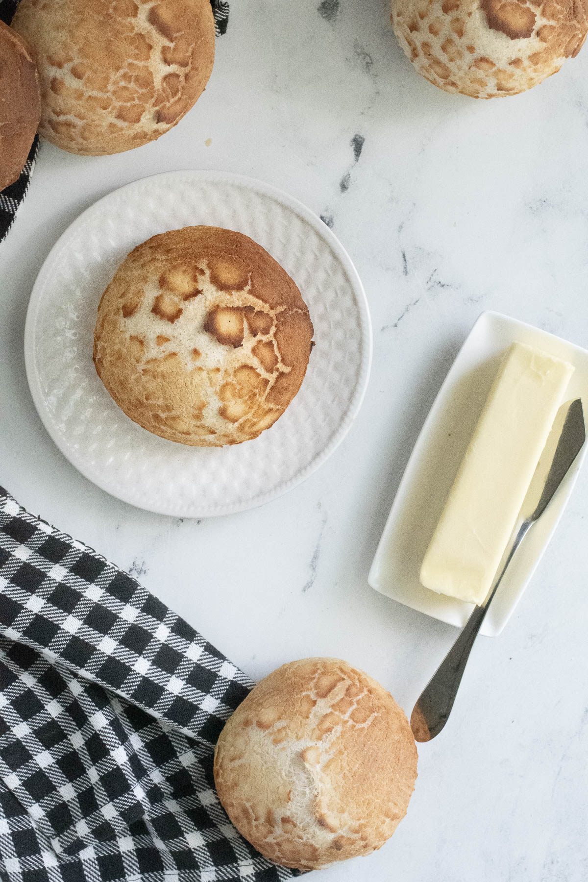 a sourdough dutch crunch roll on a white plate. Butter on a white plate. 