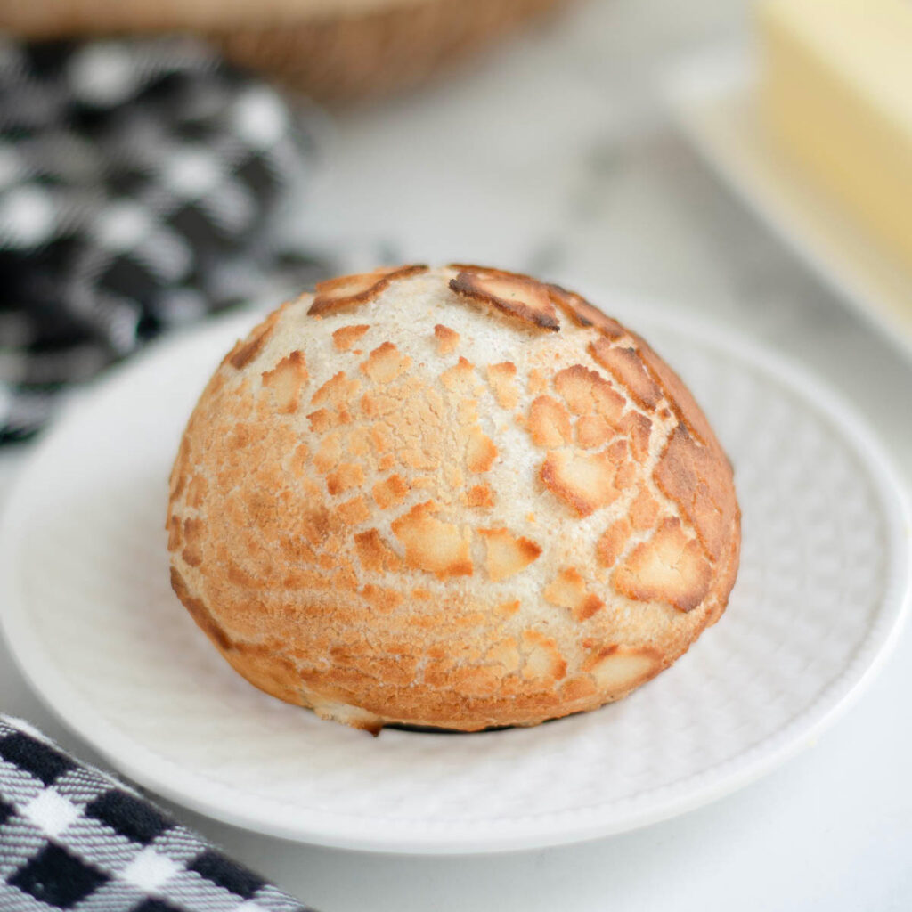 a sourdough dutch crunch roll on a white plate.