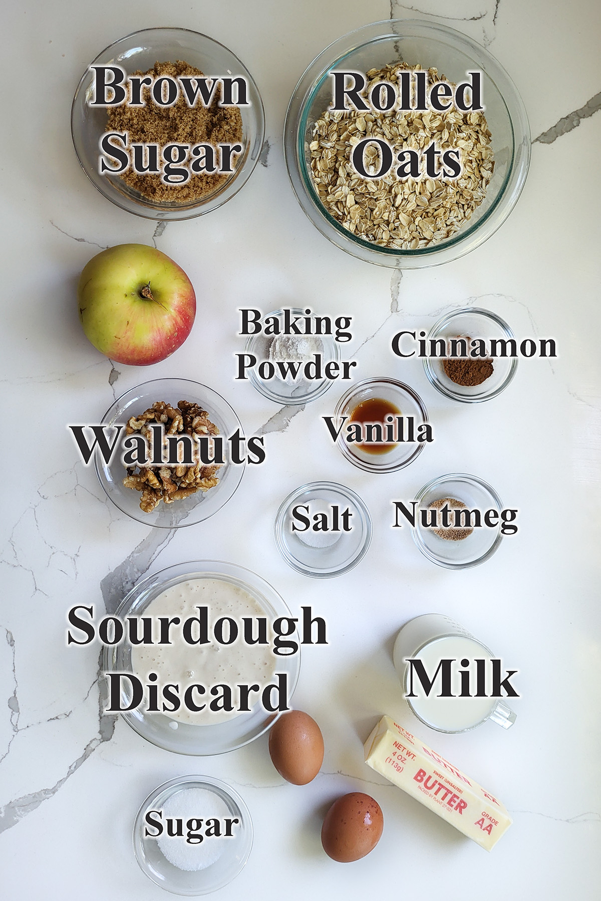 ingredients for sourdough baked oatmeal in glass bowls on a white surface.