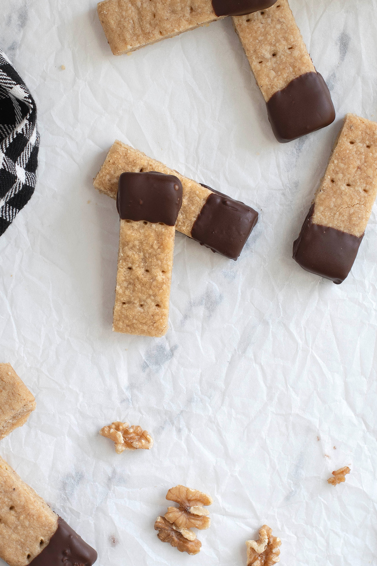 chocolate dipped walnut shortbread on a white surface. 