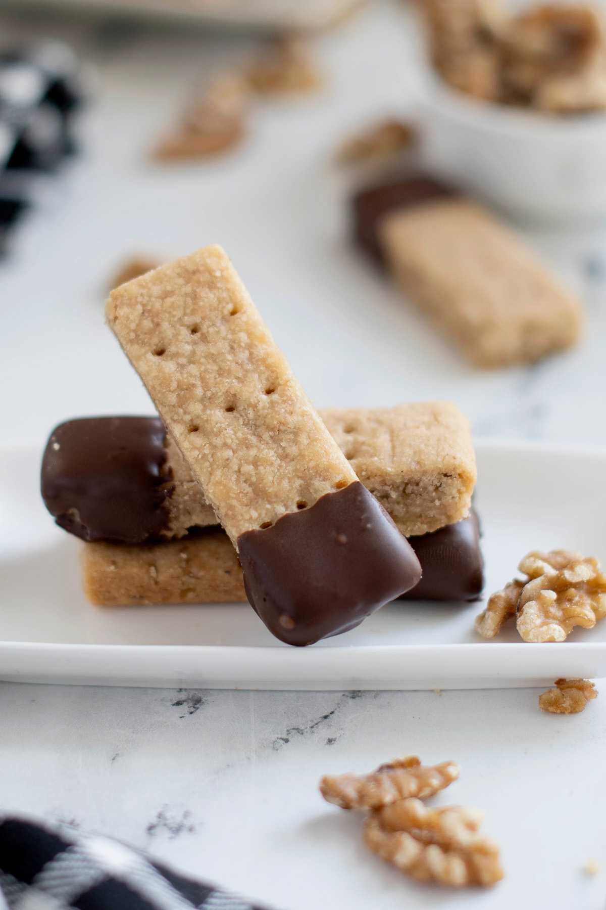 a chocolate dipped walnut shortbread cookie on a white plate.