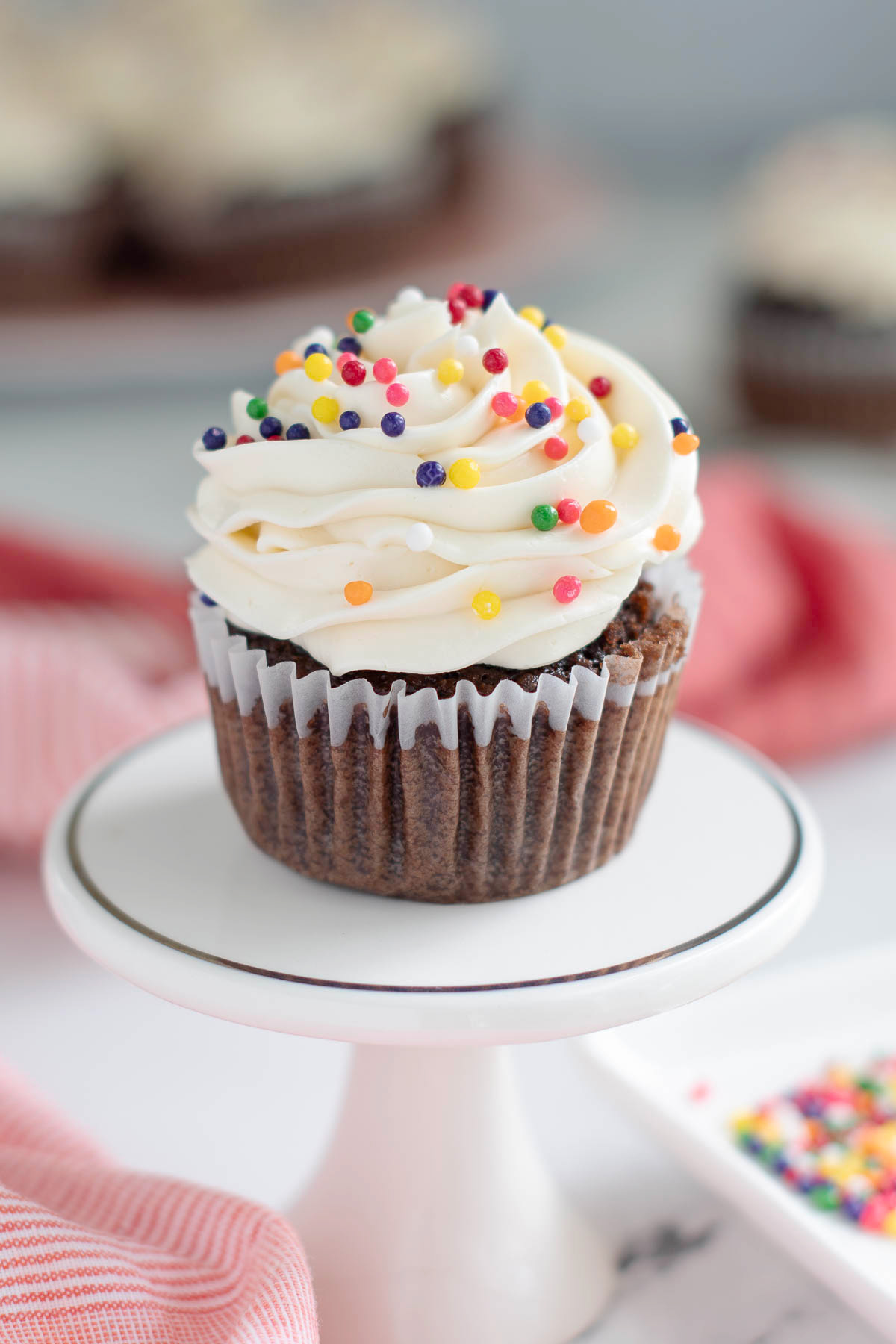 a chocolate cupcake with vanilla icing and sprinkles on a plate.