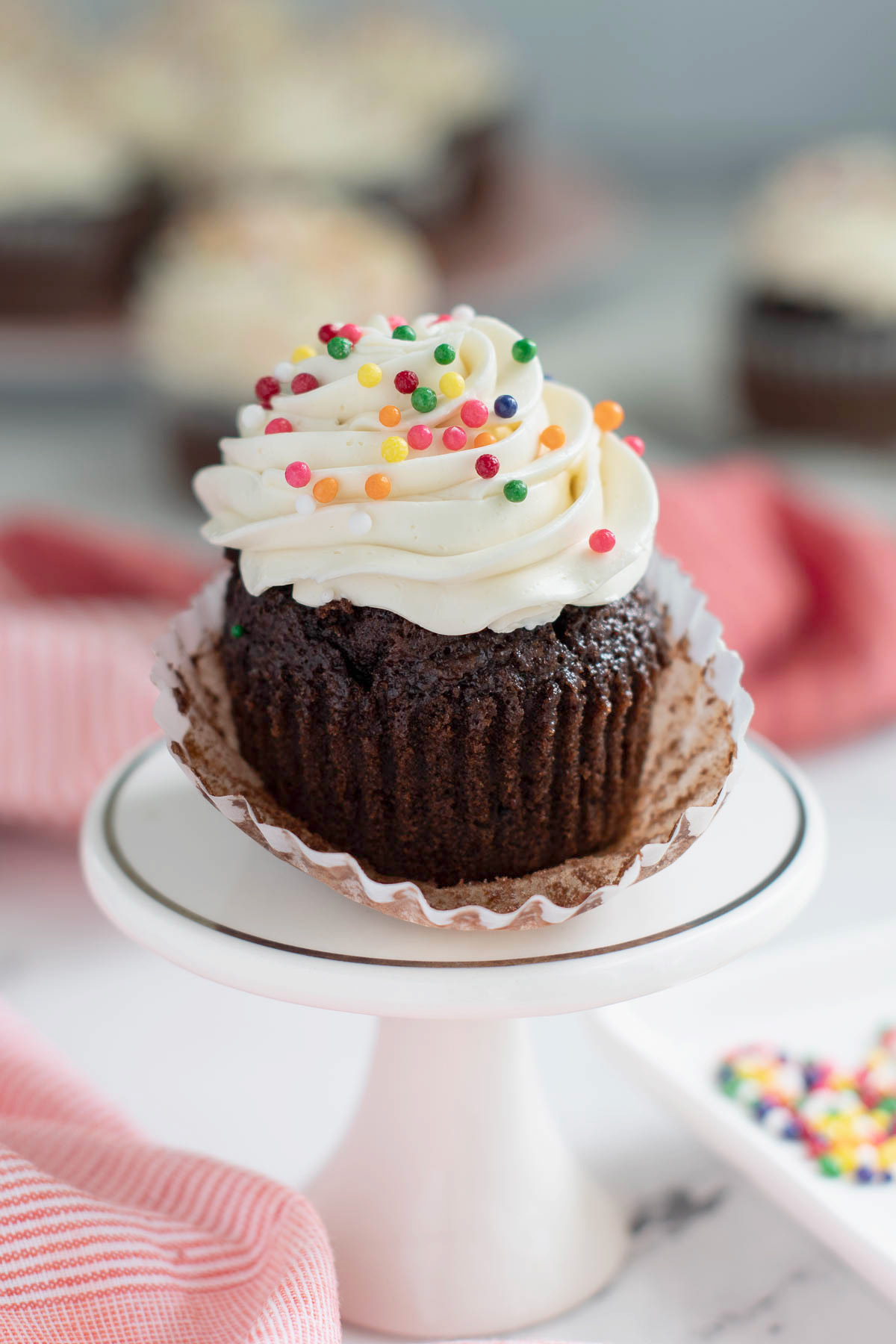 a vanilla iced chocolate cupcake on a white plate.