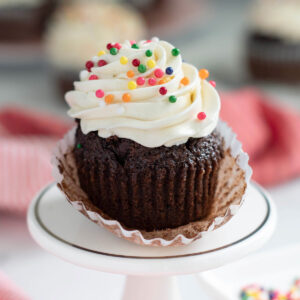 a chocolate cupcake with vanilla icing and sprinkles on a plate.