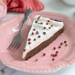 a slice of chocolate pink peppercorn tart on a pink plate.