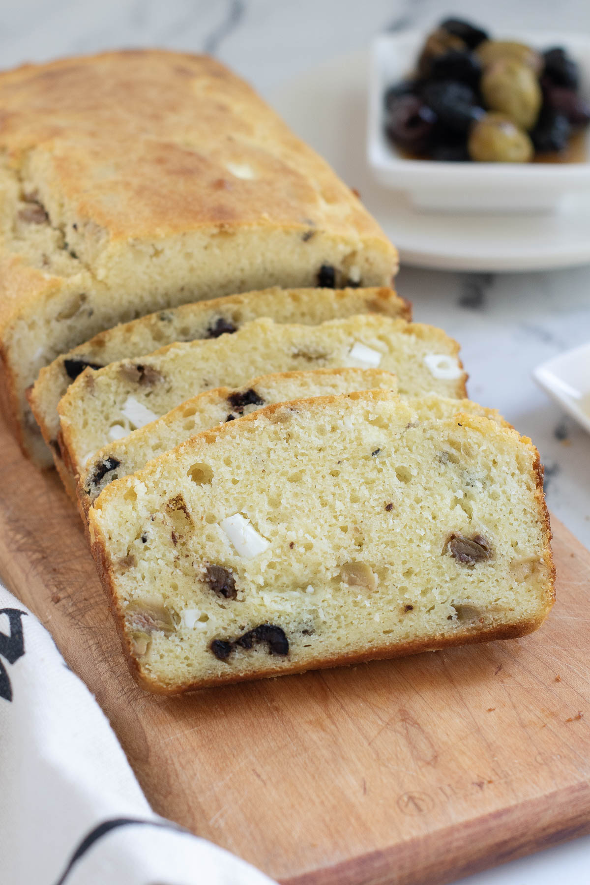 a sliced loaf of savory quickbread on a wood cutting board.