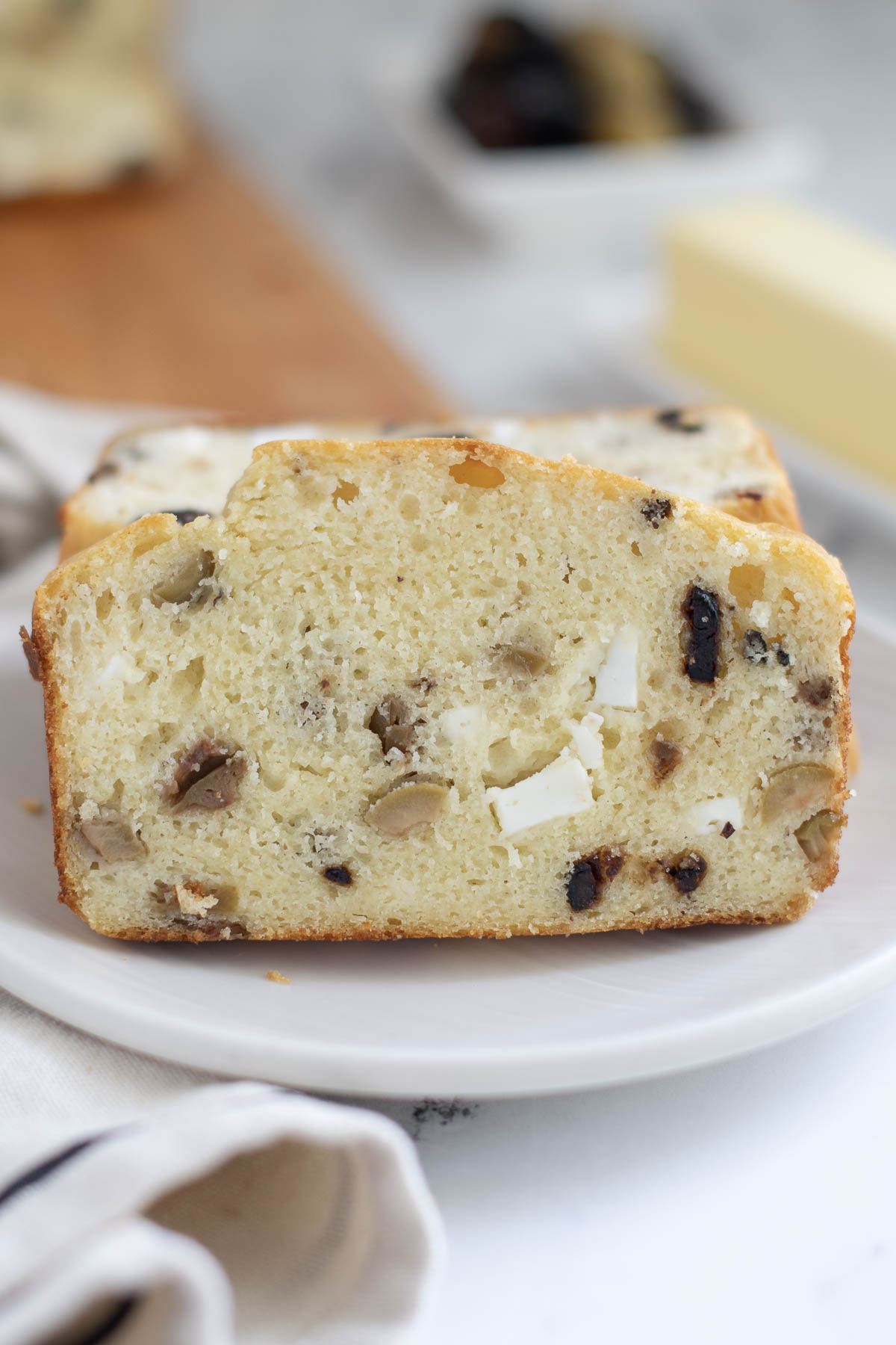 a slice of feta and olive quick bread on a white plate.