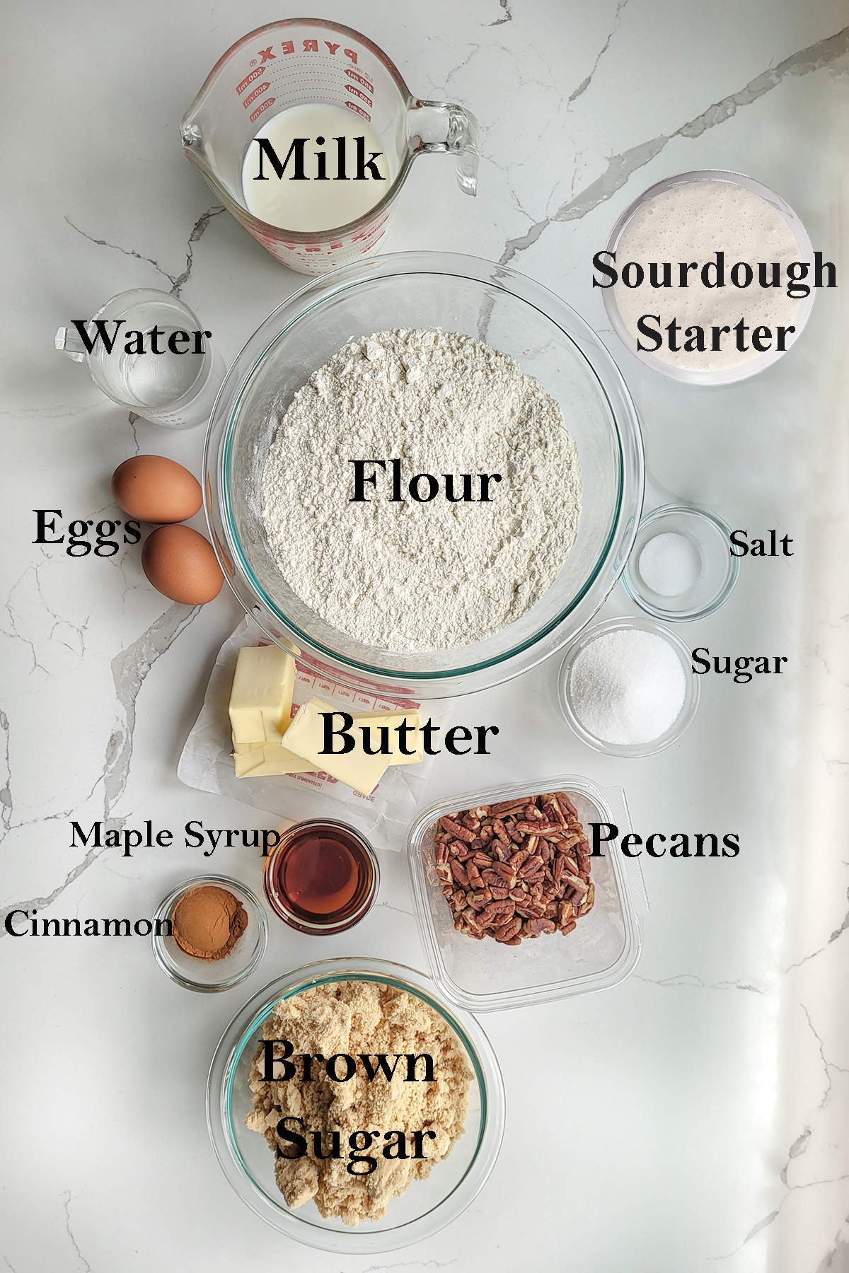 ingredients for sourdough sticky buns in glass bowls on a white surface.