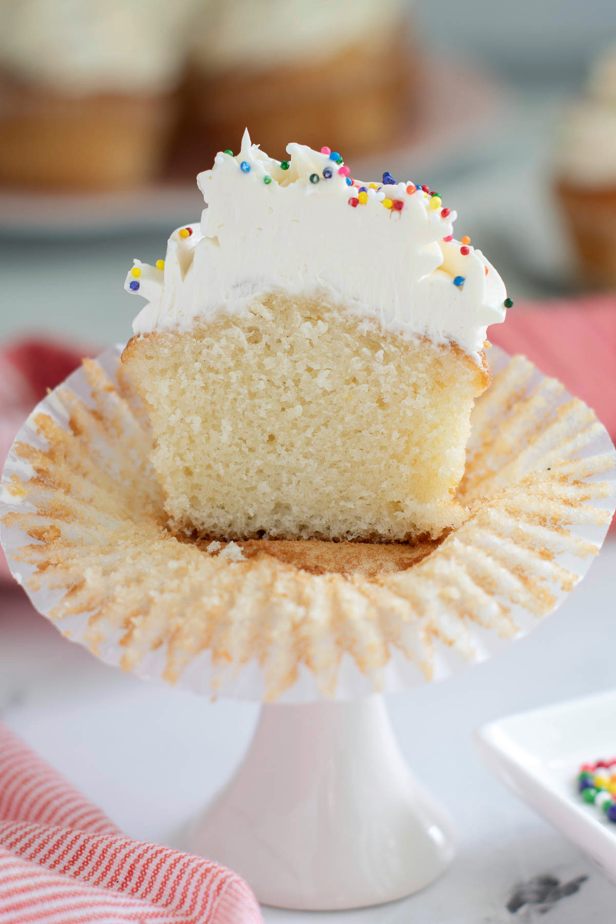 a half of a vanilla cupcake with vanilla frosting in a wrapper. 