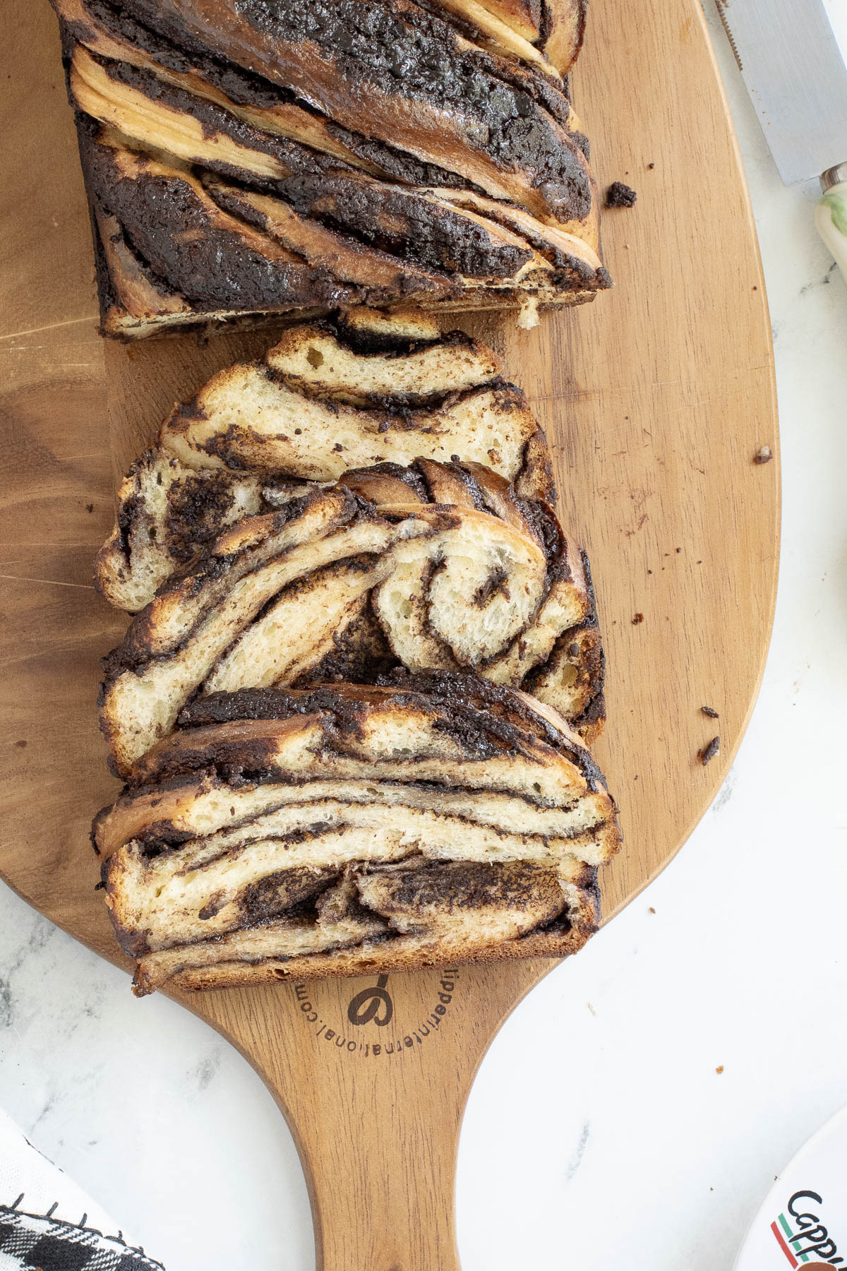 a loaf of chocolate babka with slices on a cutting board.