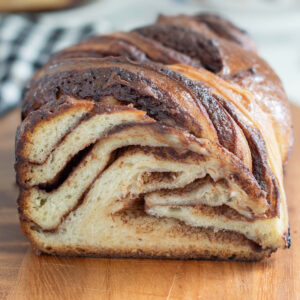 a slice of babka with malted chocolate filling on a wood surface.