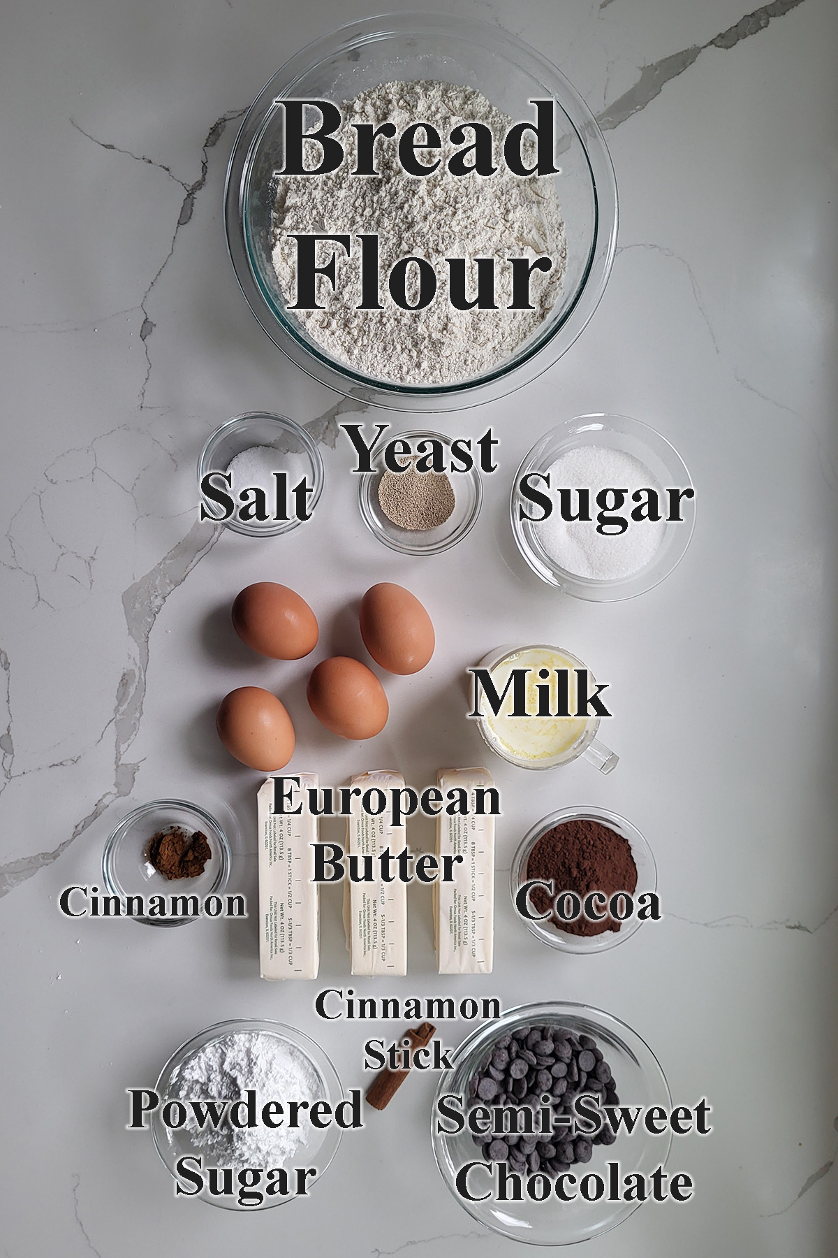 ingredients for chocolate babka in glass bowls on a white surface.