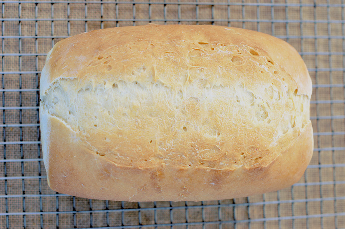 a loaf of bread cooling on a rack.