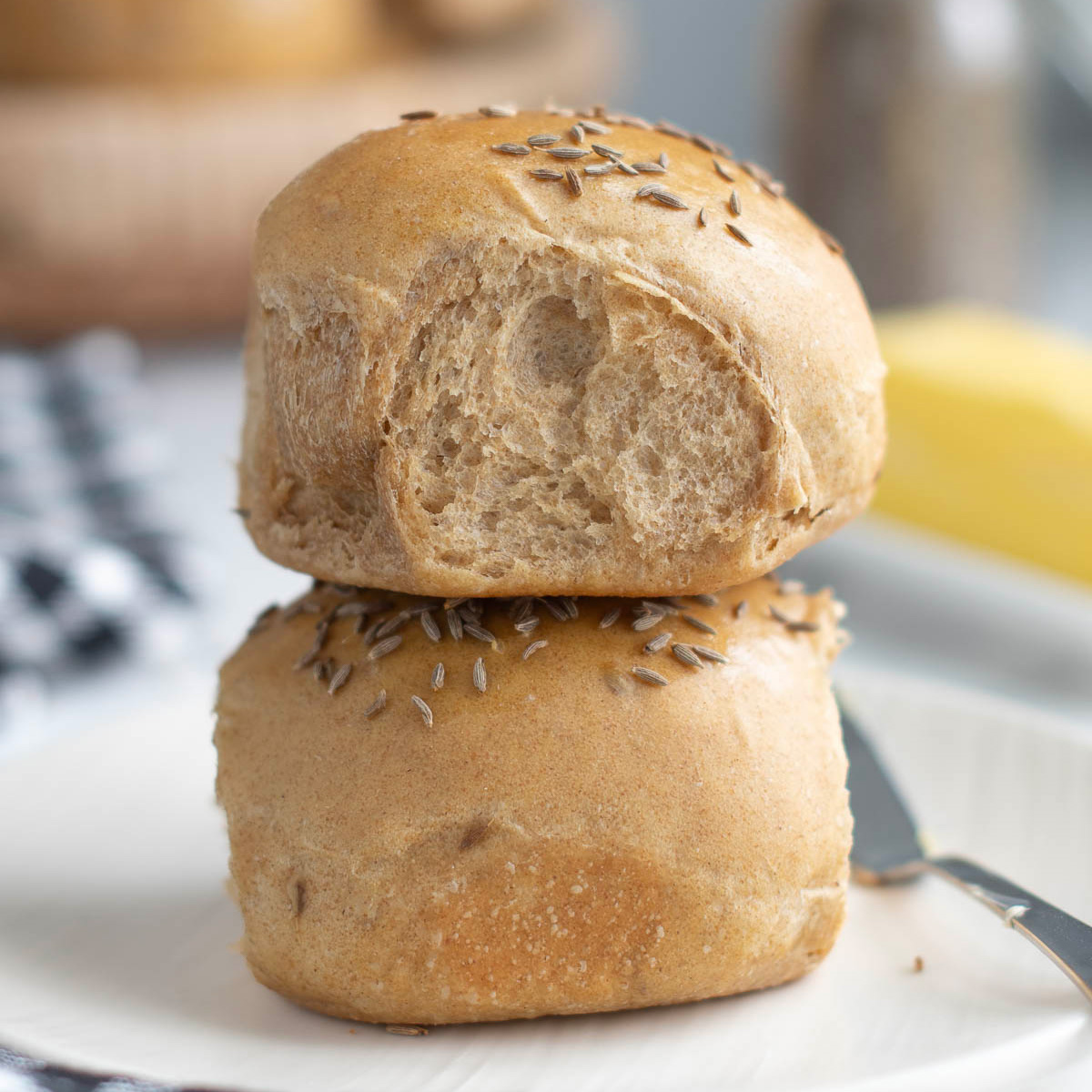 two rye dinner rolls on a white plate.
