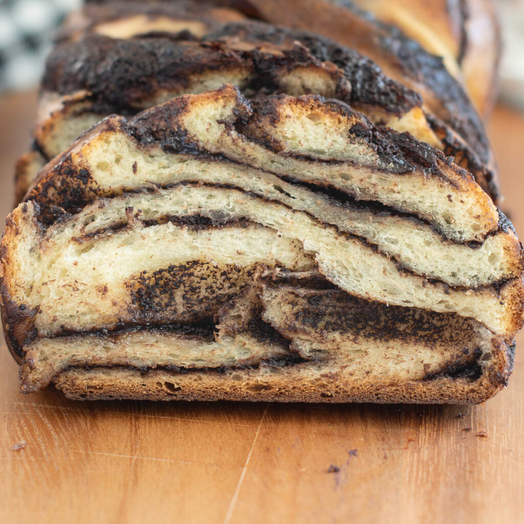 a slice of sourdough chocolate babka on a wooden cutting board.