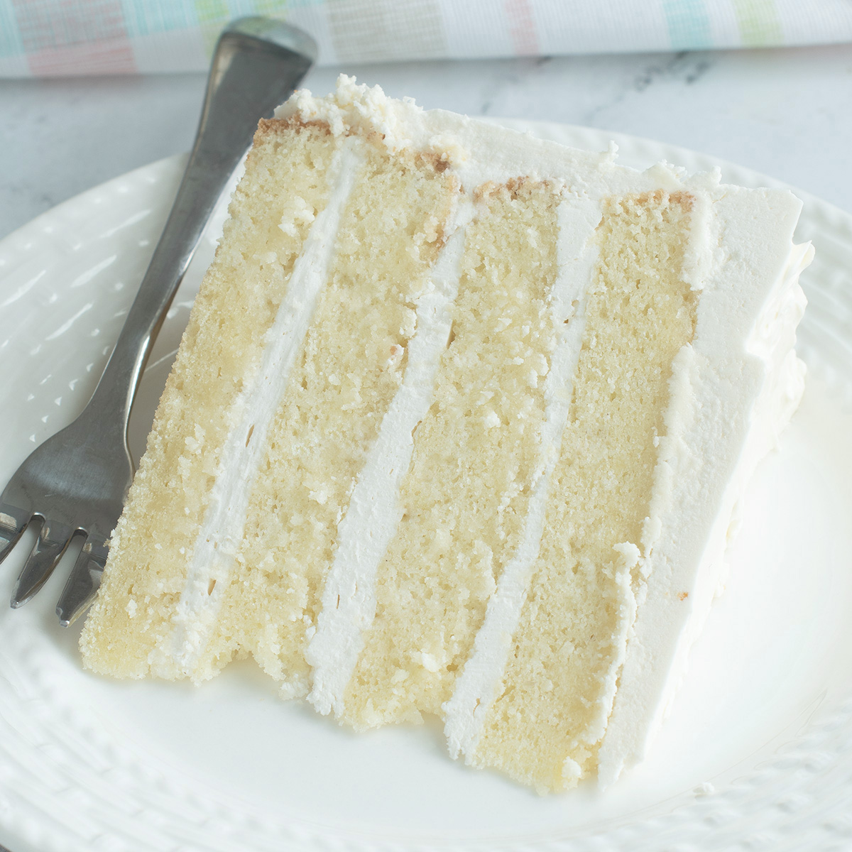 a slice of vanilla cake on a white plate.