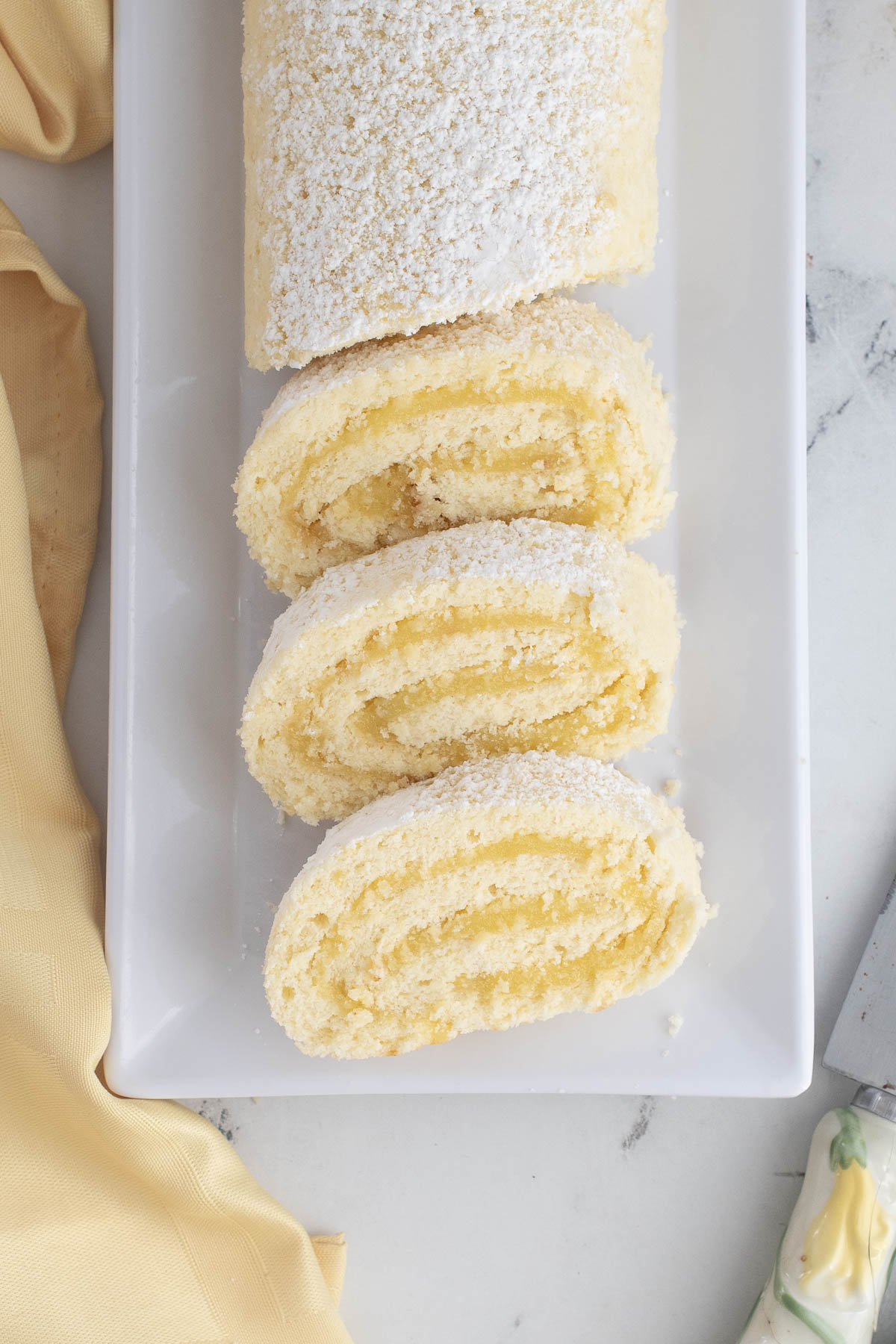 a sliced lemon roll cake on a white plate.