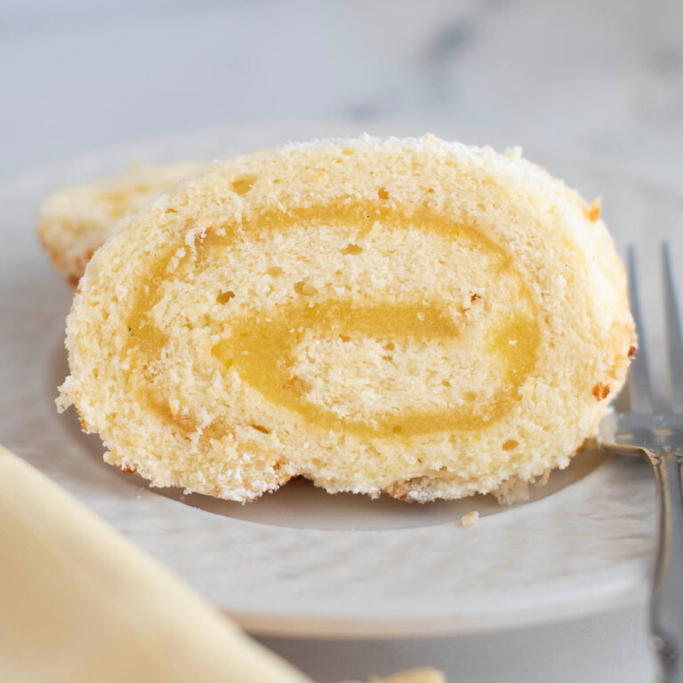 a slice of lemon swiss roll cake on a white plate.