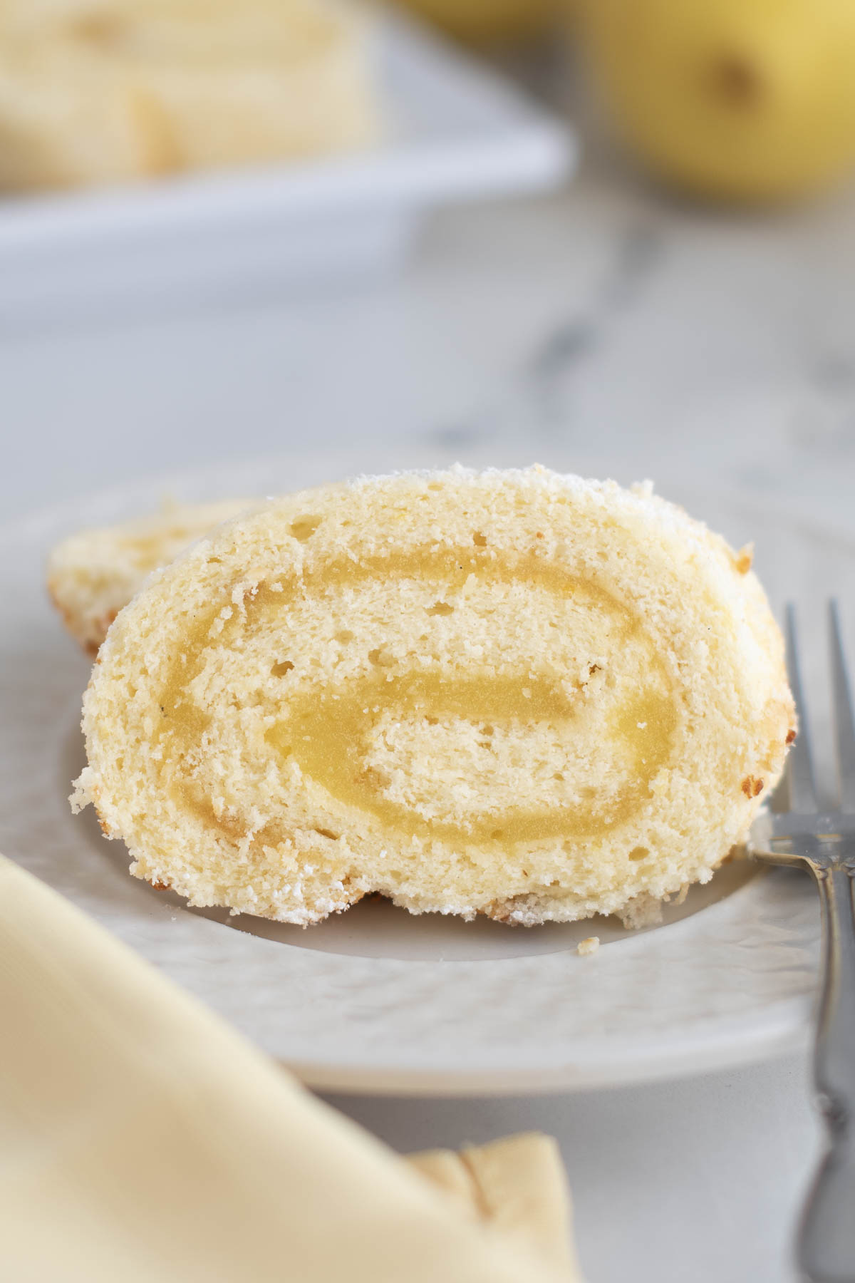 a slice of lemon swiss roll cake on a white plate.