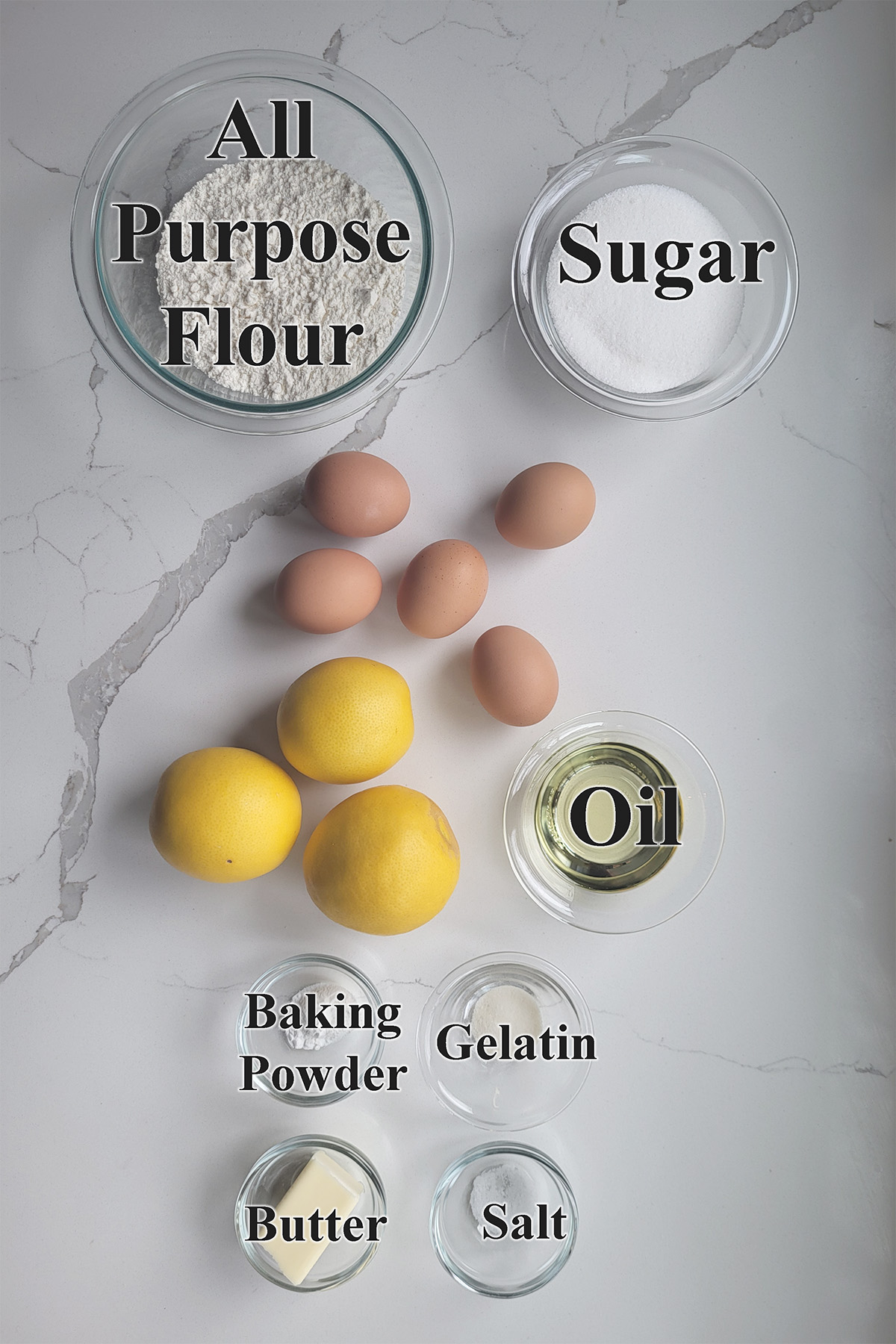 Ingredients for lemon swiss roll cake in glass bowls on a white surface.