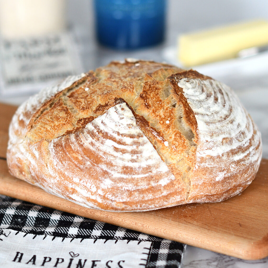 a loaf of sourdough bread on a cutting board.