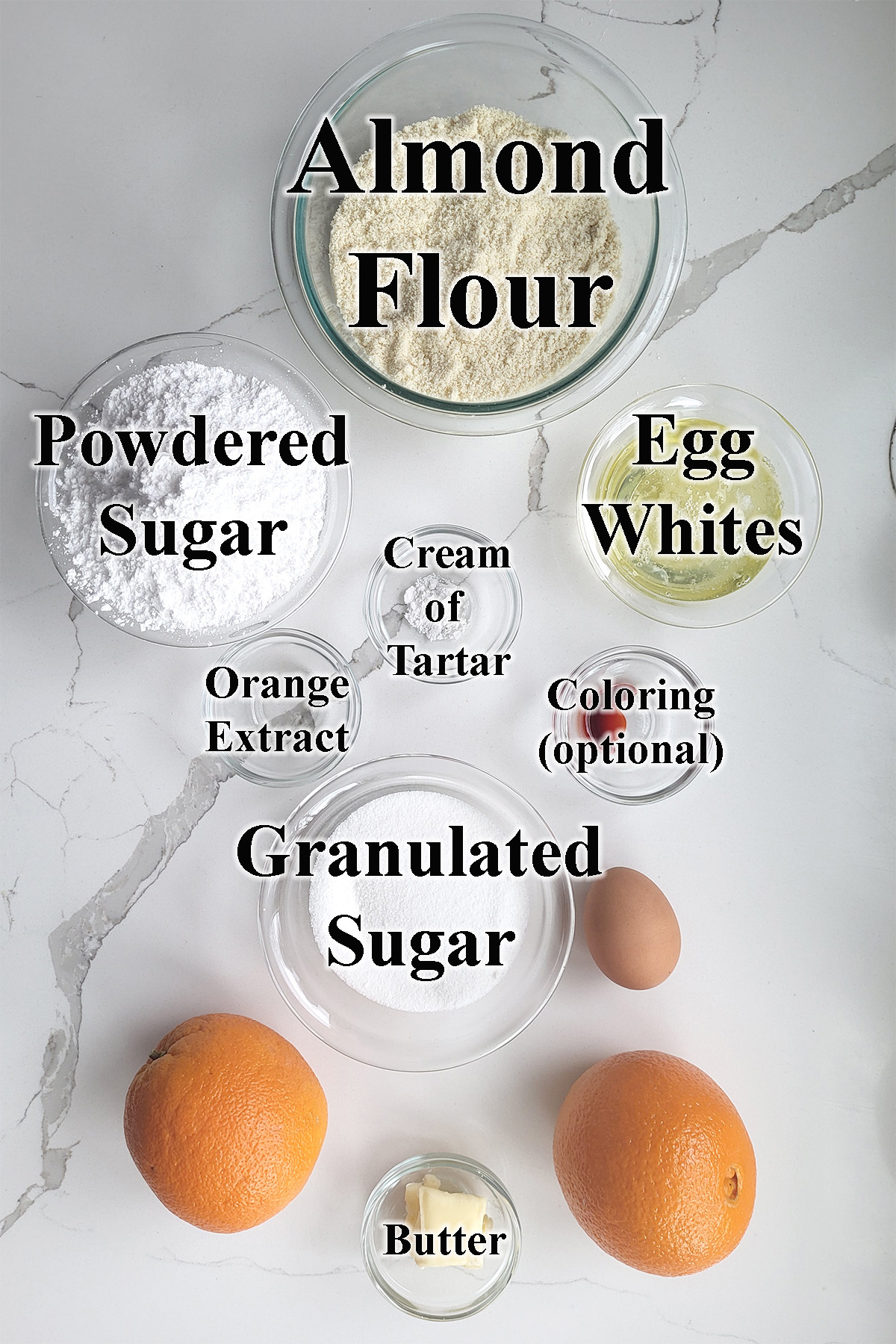 ingredients for orange macarons in glass bowls on a white surface.