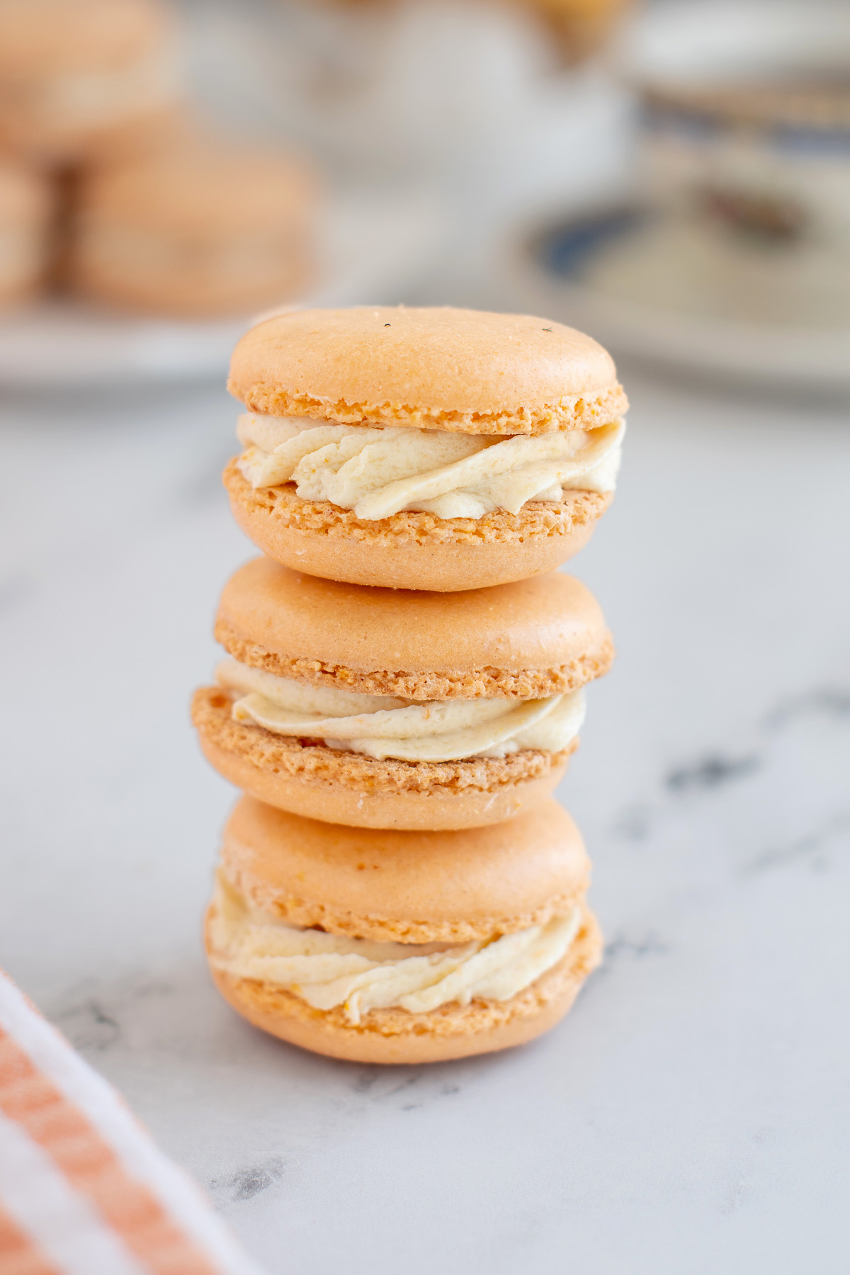 three orange macarons on a stack.