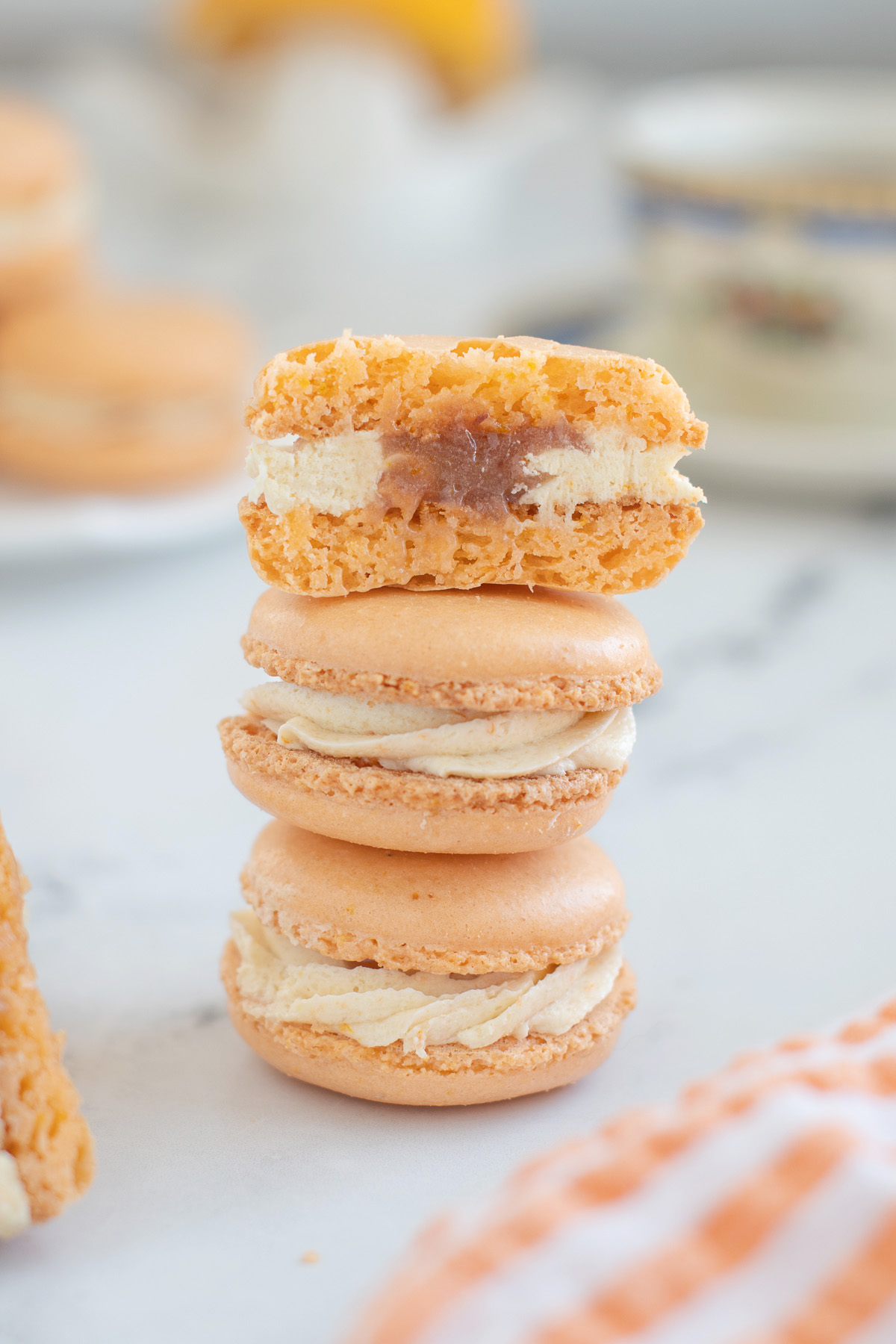 three orange macarons, one cut, in a stack.
