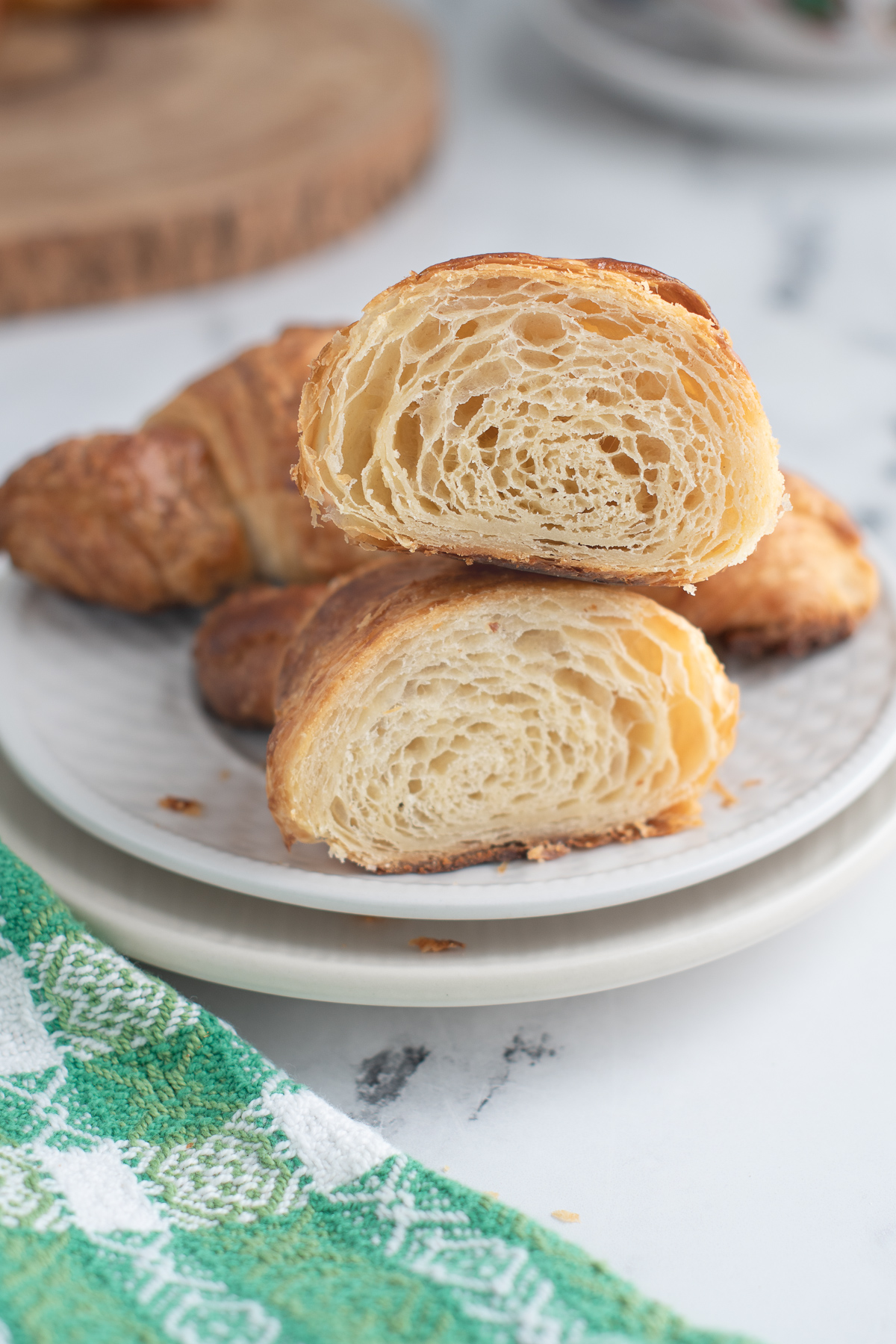 a sourdough croissant and a cut croissant on a white plate.