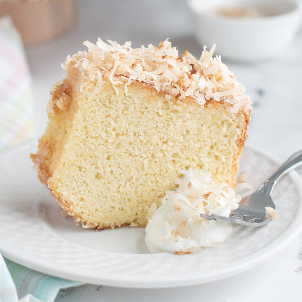 a slice of coconut chiffon cake on a plate with a fork.