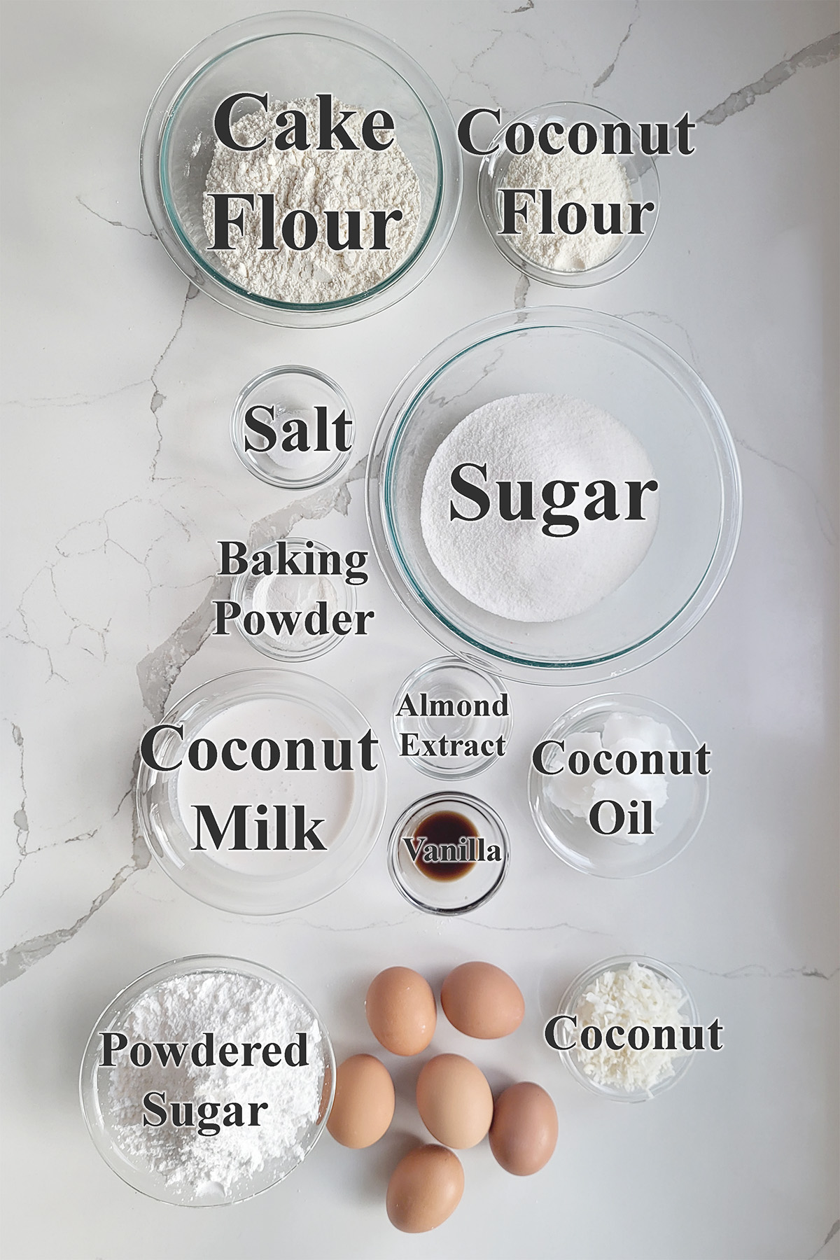 ingredients for coconut chiffon cake in glass bowls on a white surface.