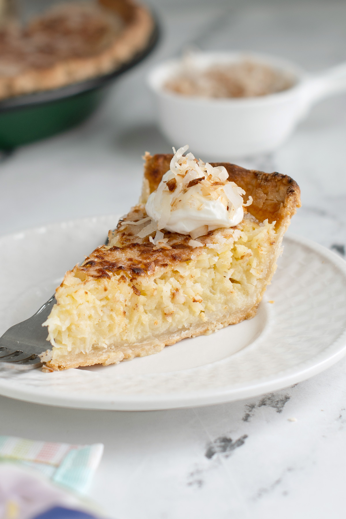 a slice of coconut custard pie on a white plate with a fork.