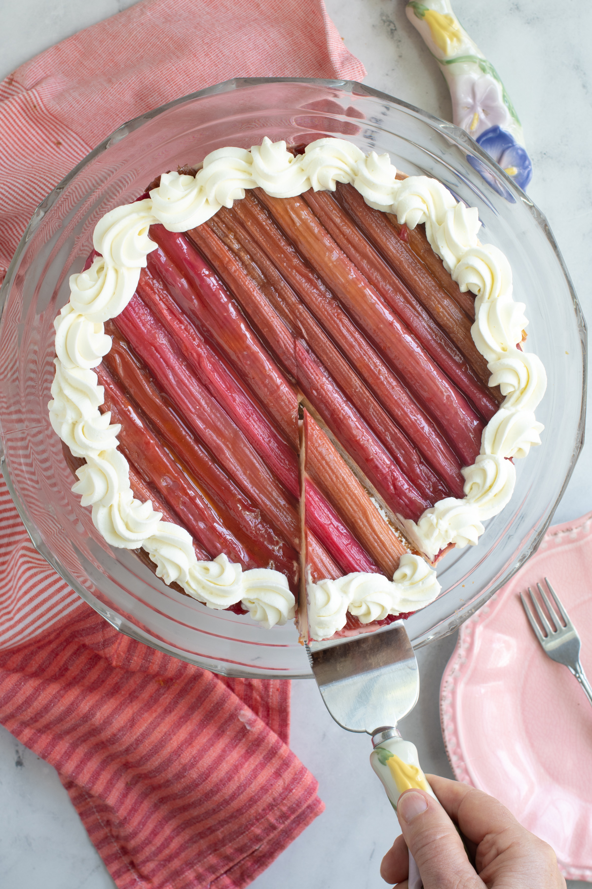 a rhubarb cheesecake on a glass cake plate.