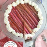 Overhead view of rhubarb cheesecake with roasted rhubarb topping, with a slice being lifted