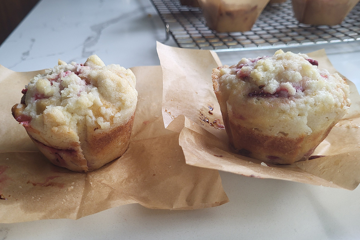 two strawberry muffins on paper side by side.