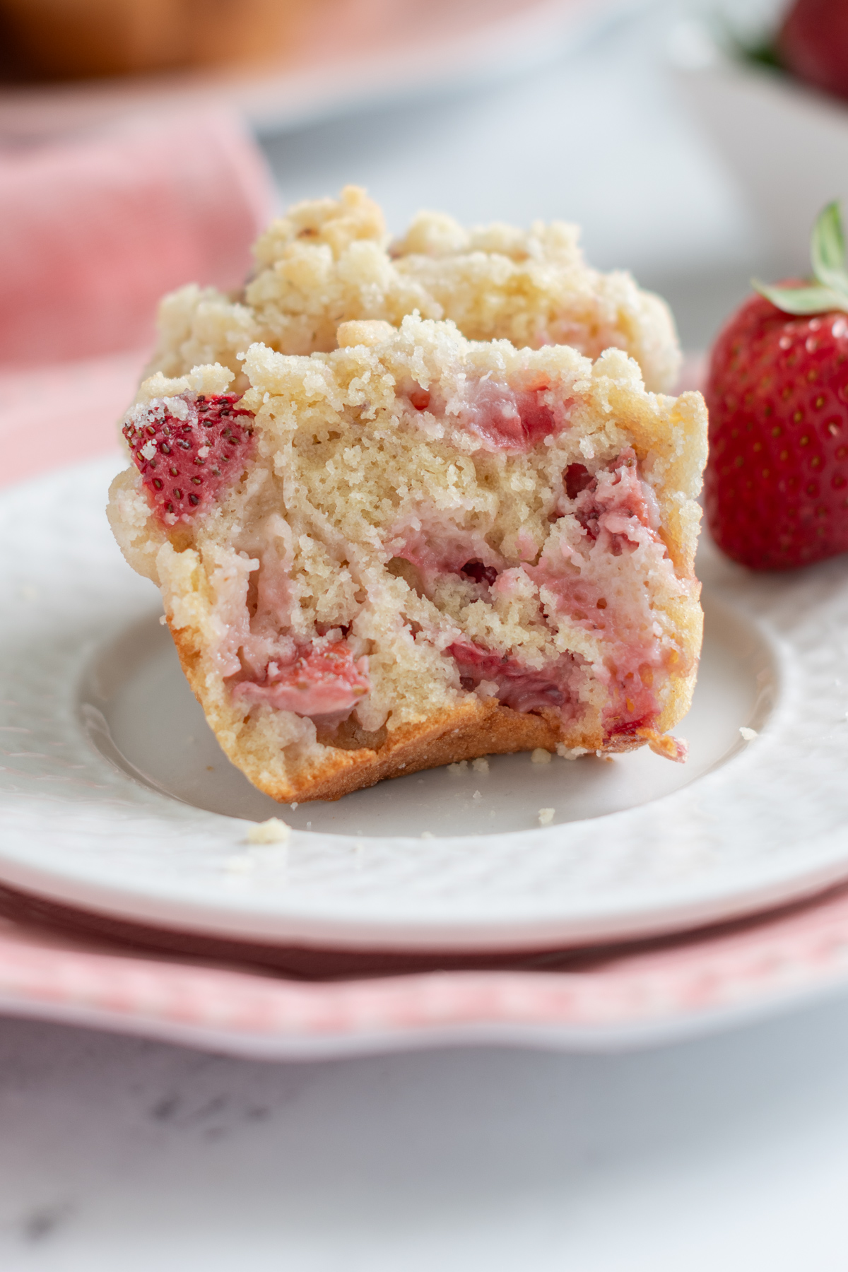 a split strawberry muffin on a white plate.