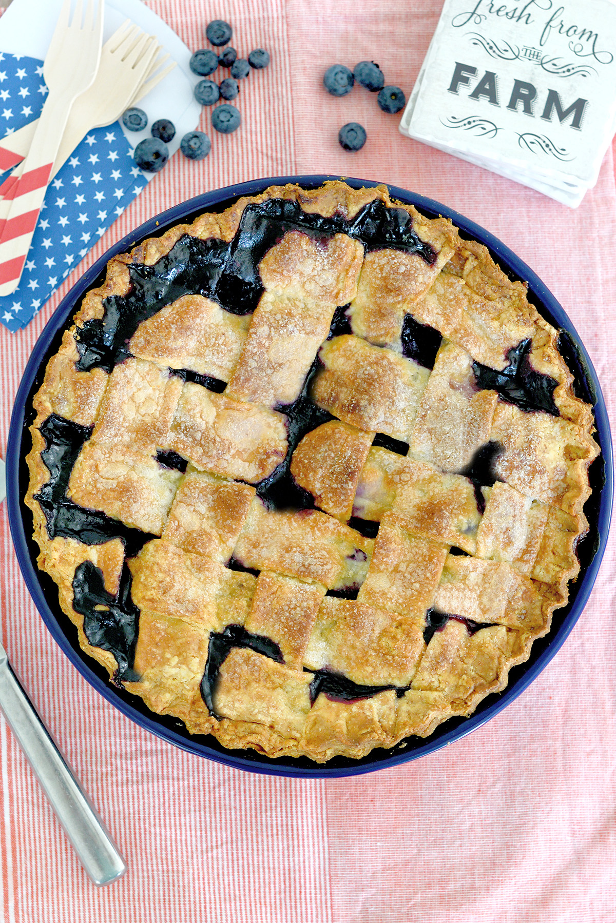 a lattice top blueberry pie on a red striped cloth.