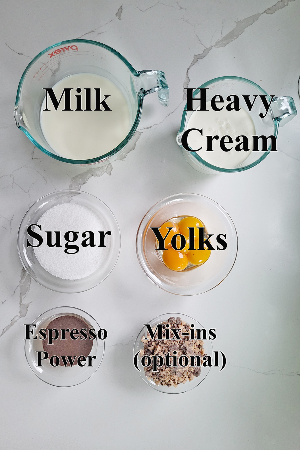 ingredients for homemade coffee ice cream in glass bowls on a white surface.