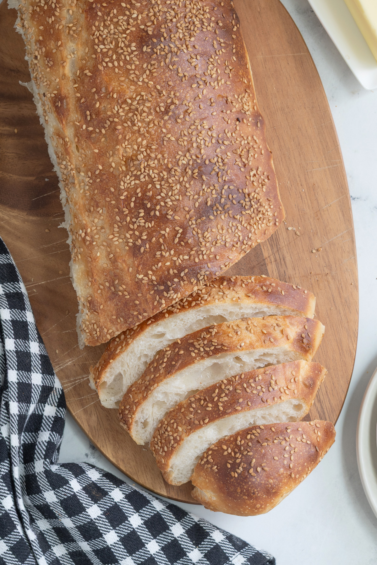 a partially sliced loaf of sourdough italian bread on a cutting board.