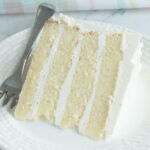 a slice of vanilla butter cake on a white plate with a fork.