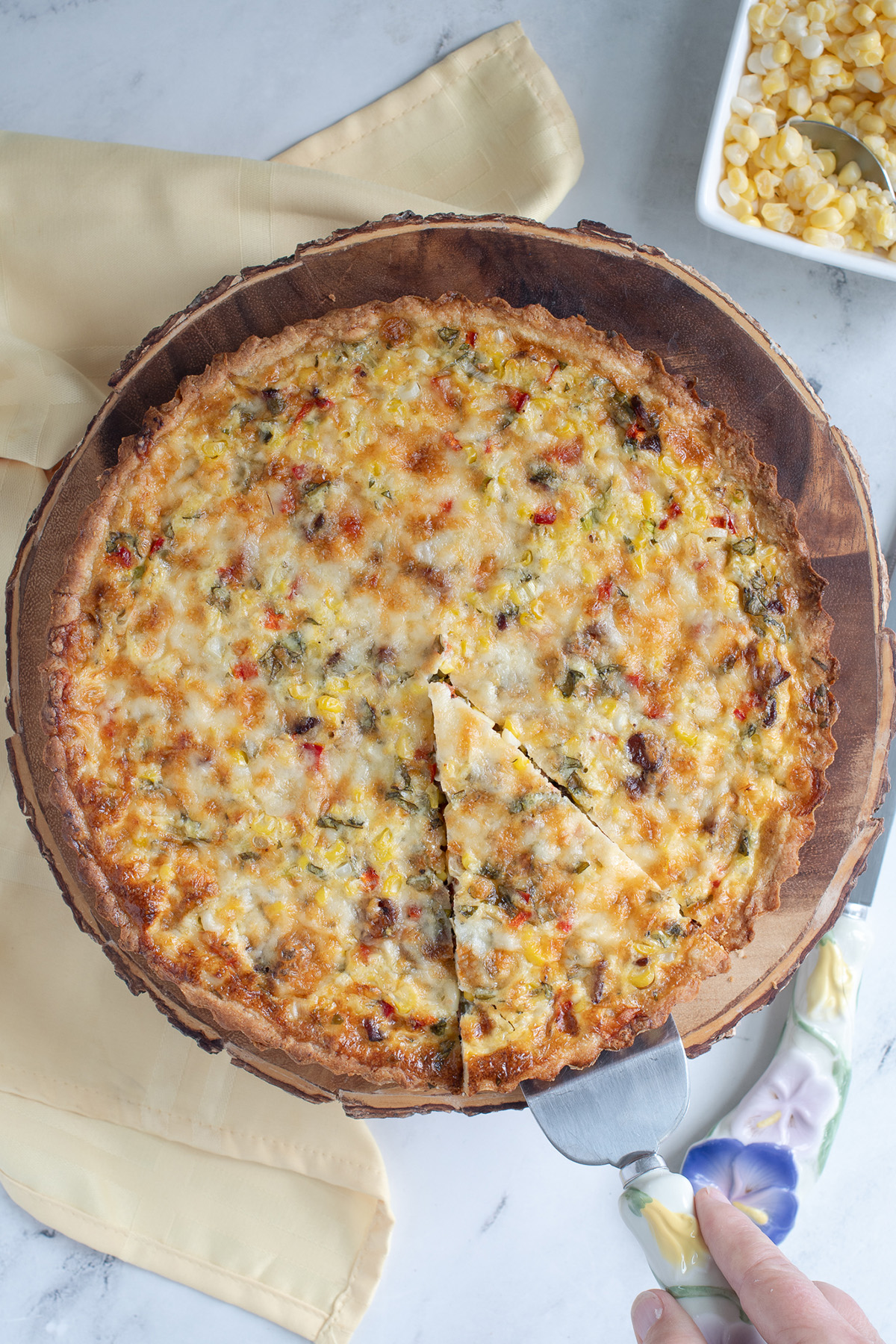a corn quiche on a wooden board with a slice cut.